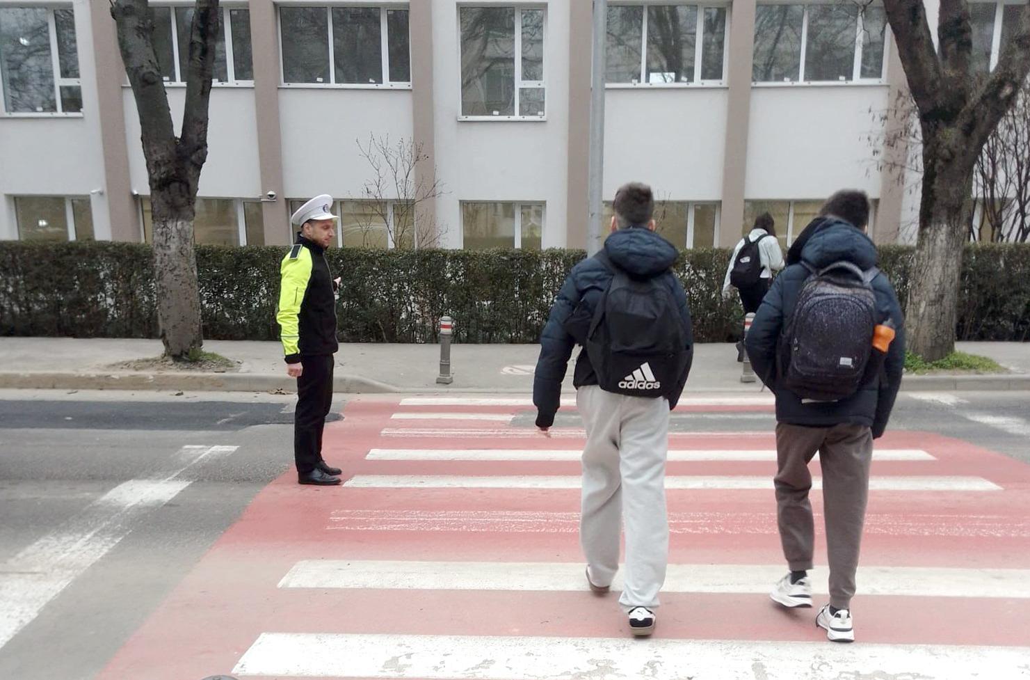 Imagine cu un polițist local care ajută pietonii în apropierea unei școli din Constanța