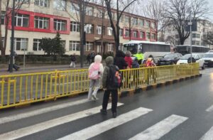 Imagine cu elevi care traversează pe trecerea de pietoni sub supravegherea unui polițist local, în Constanța