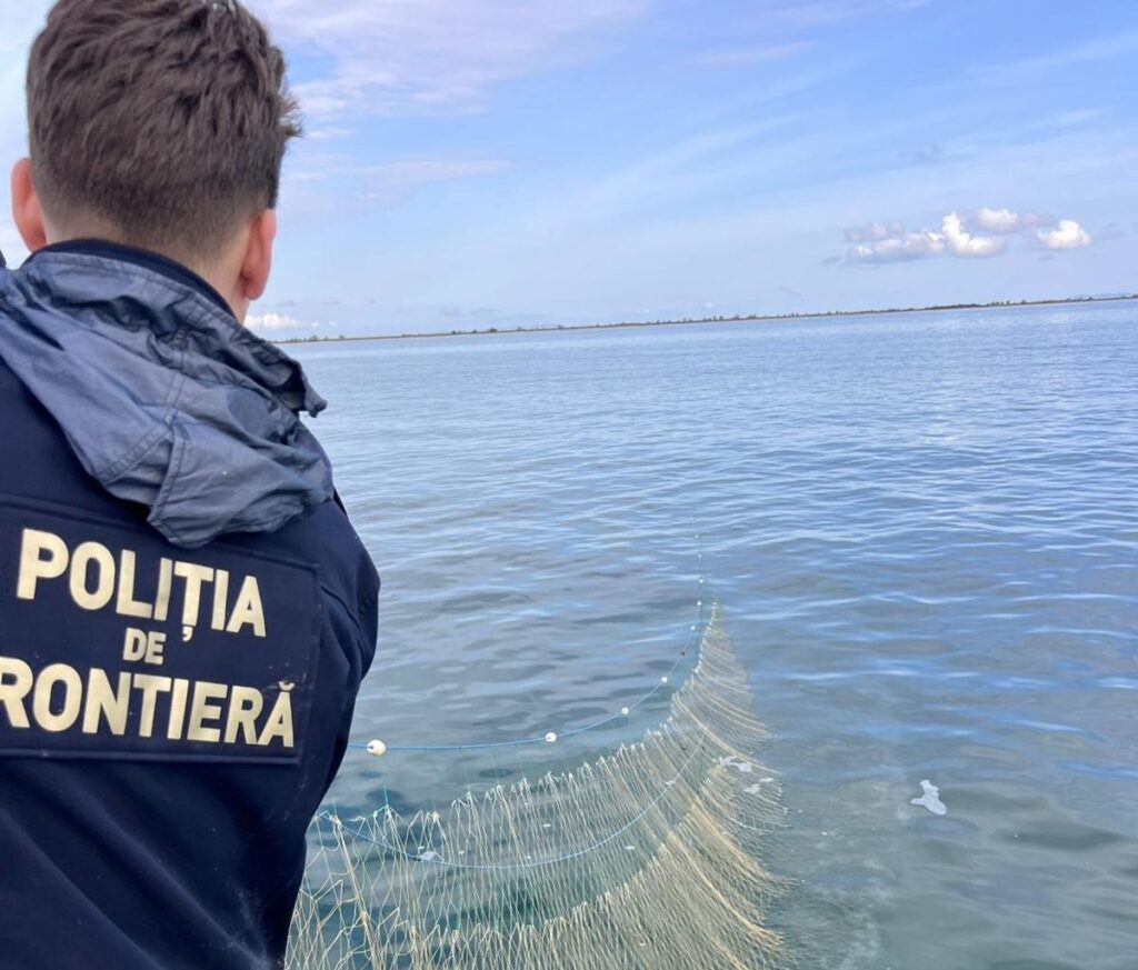 polițist de frontieră ridicând o plasă de pescuit ilegală din Marea Neagră